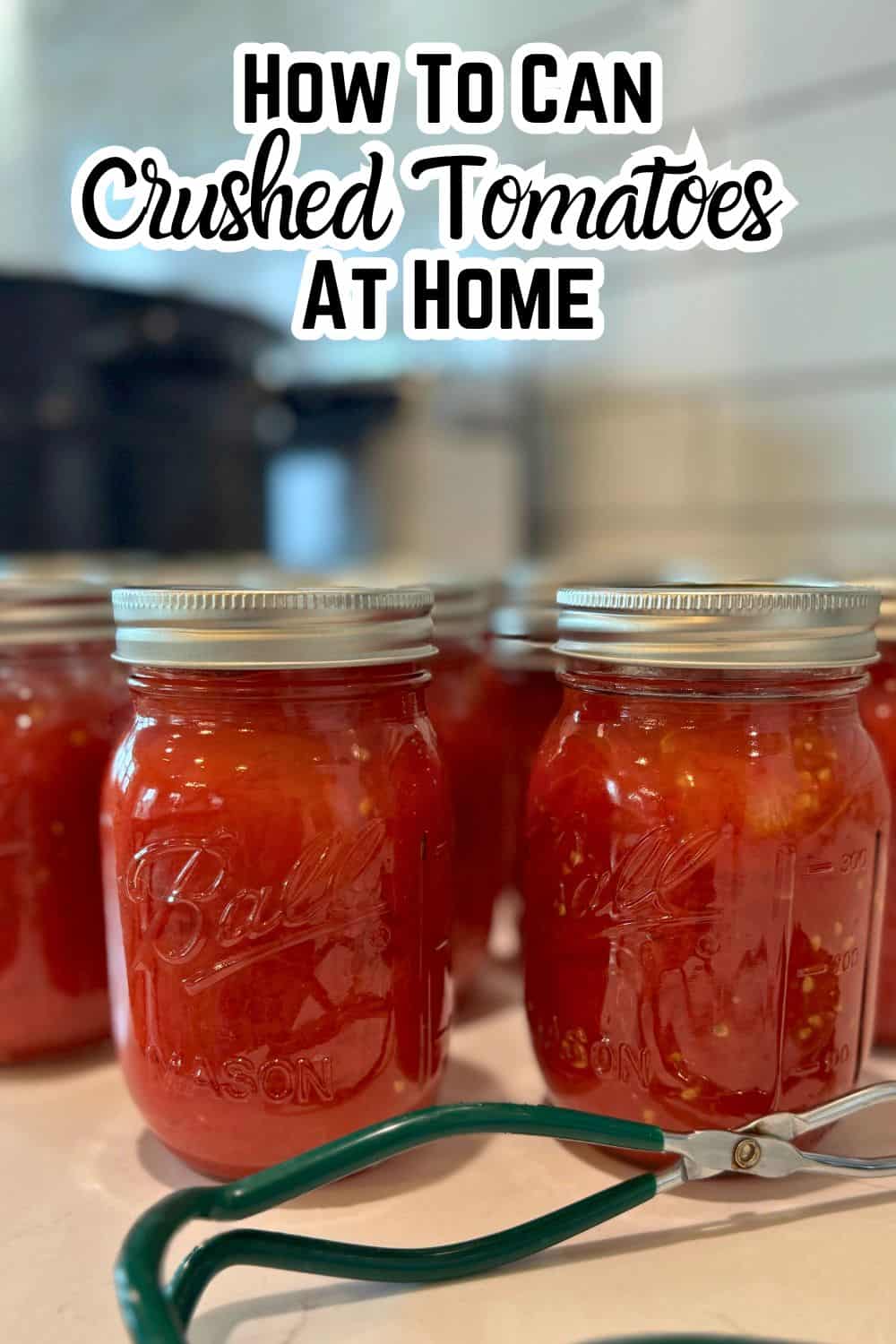 home canned crushed tomatoes in pint jars on counter by canner with text